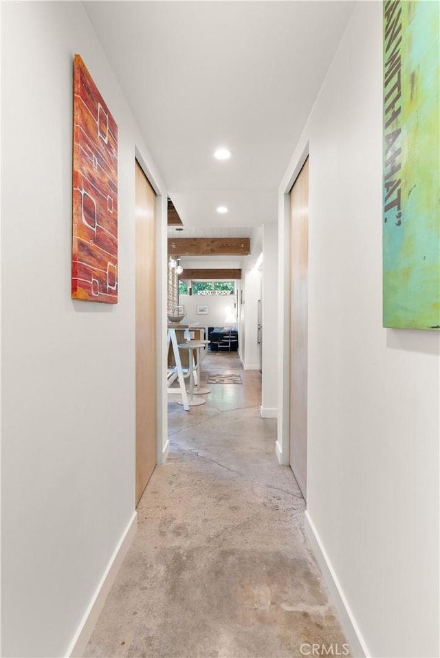 corridor with recessed lighting, concrete floors, and baseboards