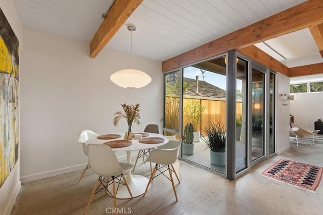 interior space featuring concrete flooring, beamed ceiling, a wealth of natural light, and baseboards