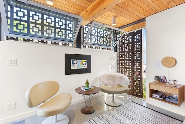 sitting room featuring wooden ceiling, beam ceiling, and baseboards