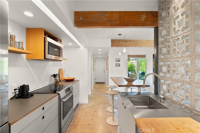 kitchen featuring stainless steel appliances, a sink, beam ceiling, open shelves, and tasteful backsplash