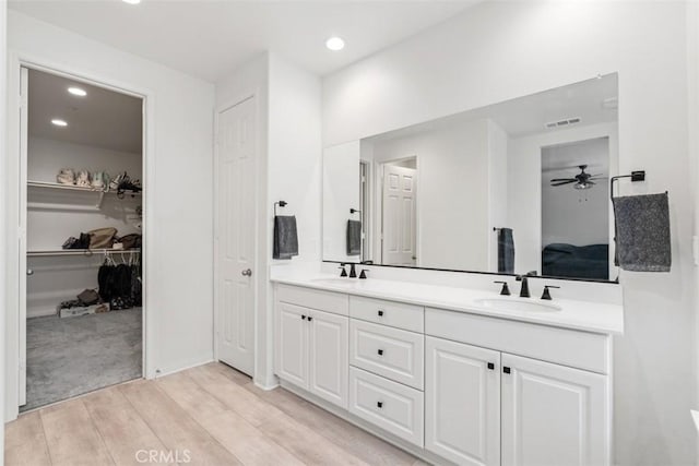 bathroom featuring recessed lighting, double vanity, a sink, and wood finished floors