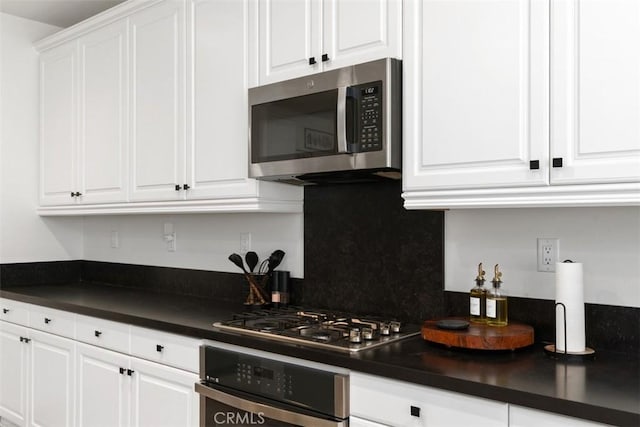 kitchen featuring dark countertops, white cabinetry, appliances with stainless steel finishes, and decorative backsplash