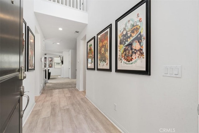 hall featuring baseboards, light wood finished floors, and recessed lighting