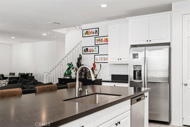 kitchen with dark countertops, appliances with stainless steel finishes, open floor plan, and a sink