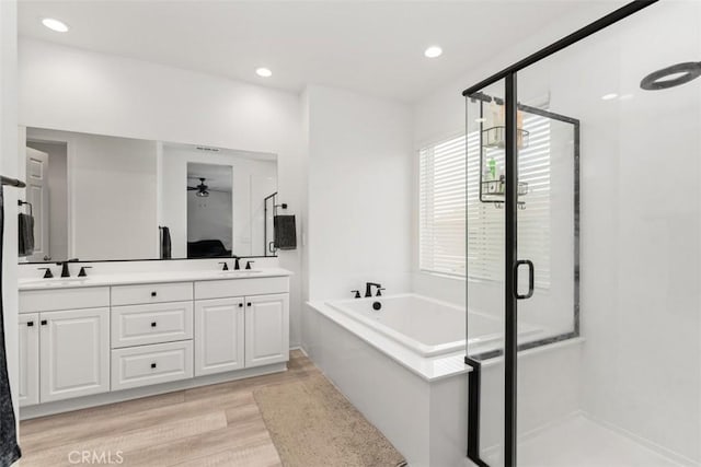 full bathroom featuring double vanity, wood finished floors, a shower stall, and a bath