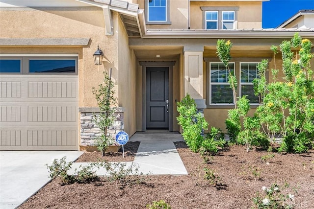 entrance to property with a garage and stucco siding