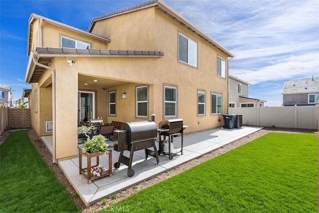 rear view of property featuring a patio area, a lawn, a fenced backyard, and stucco siding