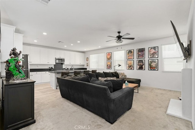 living room featuring light carpet, ceiling fan, visible vents, and recessed lighting