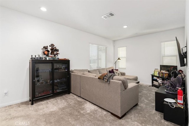 carpeted living room featuring baseboards, visible vents, and a healthy amount of sunlight