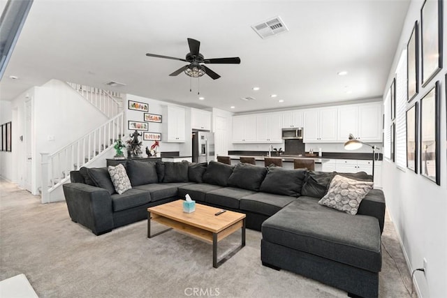 living area with a ceiling fan, recessed lighting, visible vents, and stairs