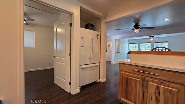 kitchen featuring baseboards, visible vents, brown cabinetry, dark wood-style flooring, and freestanding refrigerator