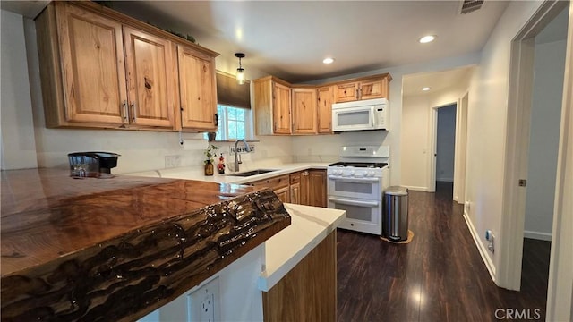 kitchen featuring recessed lighting, visible vents, dark wood-type flooring, a sink, and white appliances