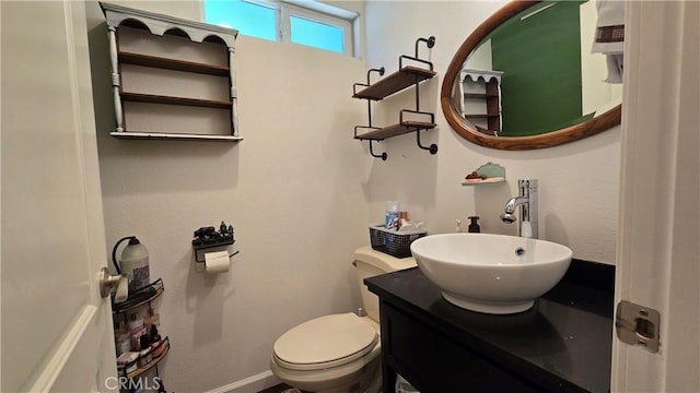 bathroom with baseboards, vanity, and toilet