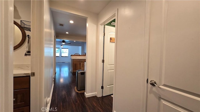 corridor with dark wood-style floors, baseboards, visible vents, and recessed lighting