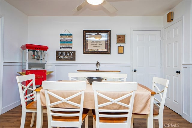 dining room featuring a wainscoted wall, ceiling fan, and wood finished floors