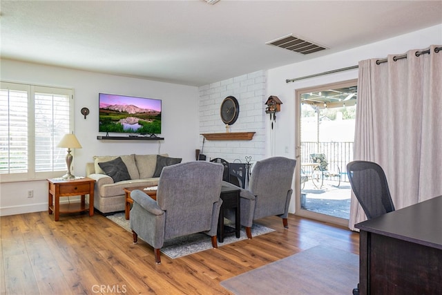 living area with a fireplace, wood finished floors, visible vents, and baseboards