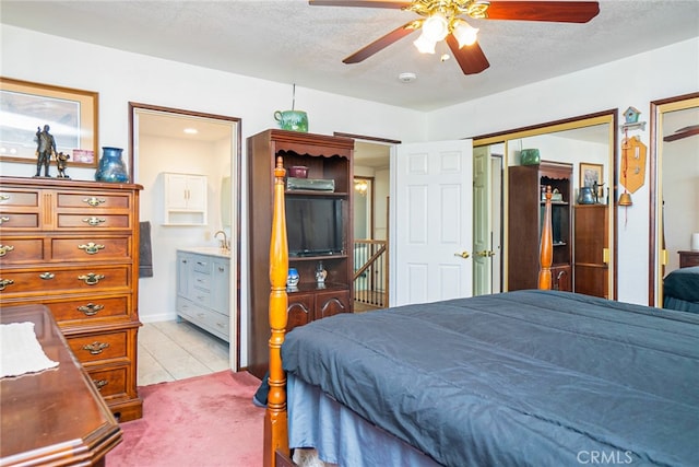 bedroom featuring multiple closets, light carpet, a textured ceiling, and light tile patterned flooring