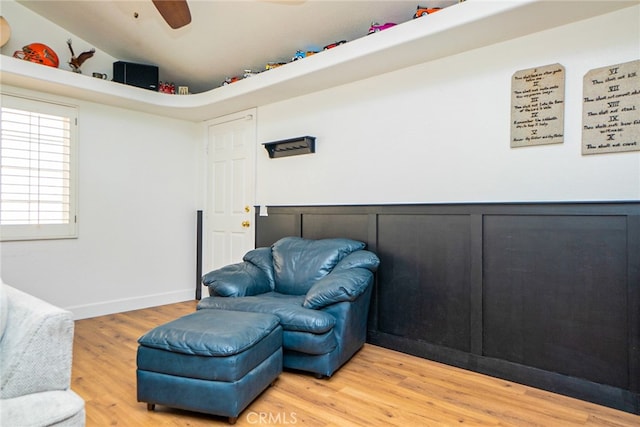 sitting room featuring a wainscoted wall, ceiling fan, and wood finished floors