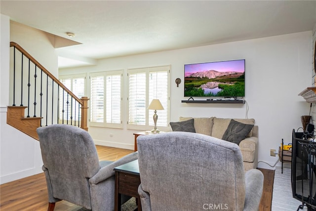 living area with stairway, baseboards, and wood finished floors