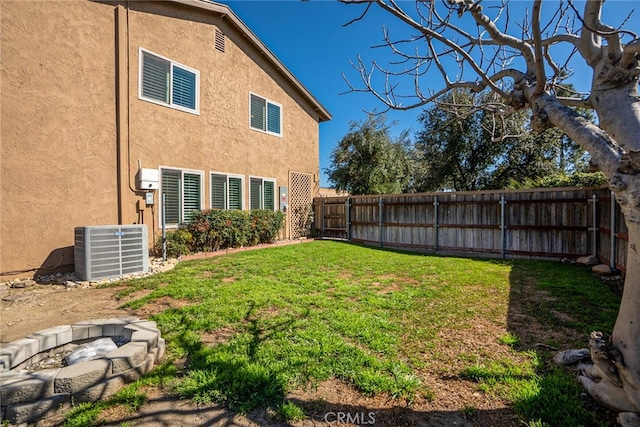 view of yard featuring an outdoor fire pit, central AC, and a fenced backyard