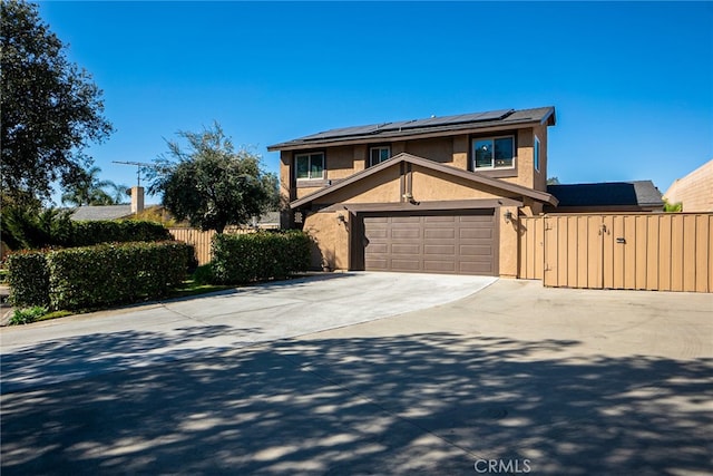 traditional-style house with stucco siding, concrete driveway, a gate, roof mounted solar panels, and fence