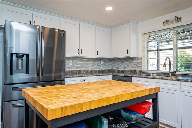 kitchen featuring butcher block counters, backsplash, white cabinets, a sink, and stainless steel fridge with ice dispenser