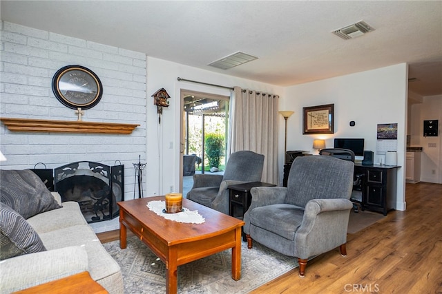 living area with visible vents, a fireplace, and wood finished floors