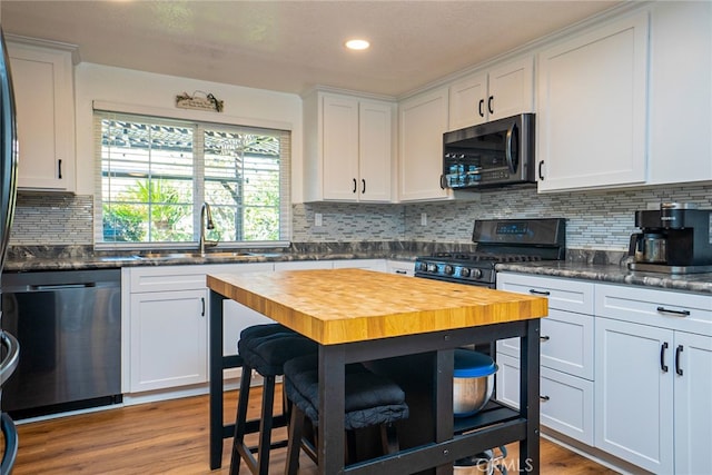 kitchen featuring stainless steel appliances, wood finished floors, a sink, and wooden counters