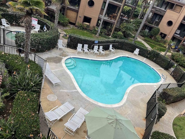 pool with a patio area and fence