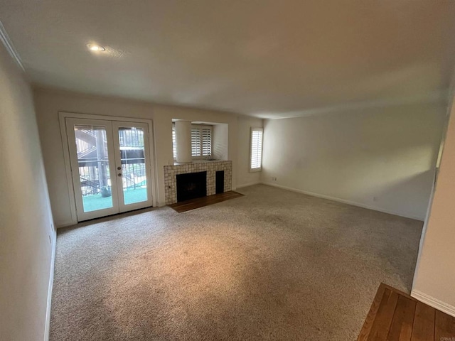 unfurnished living room featuring carpet floors, a tile fireplace, french doors, and baseboards