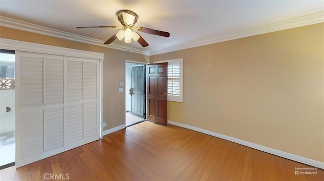 unfurnished bedroom with ornamental molding, a closet, baseboards, and wood finished floors