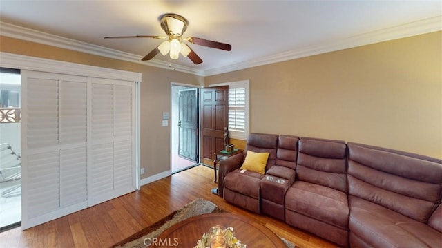 living room featuring ornamental molding, a ceiling fan, baseboards, and wood finished floors