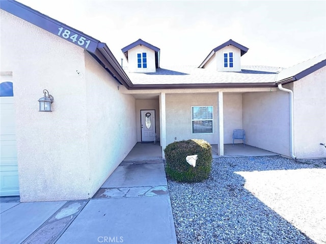 entrance to property featuring a garage and stucco siding