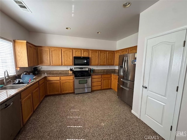 kitchen with appliances with stainless steel finishes, brown cabinets, a sink, and visible vents