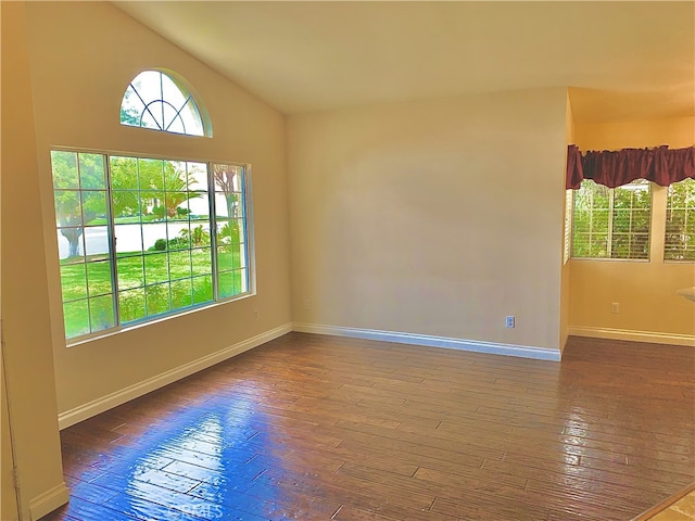 spare room featuring vaulted ceiling, hardwood / wood-style floors, and baseboards