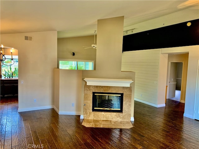 unfurnished living room featuring baseboards, visible vents, a tiled fireplace, hardwood / wood-style flooring, and ceiling fan with notable chandelier