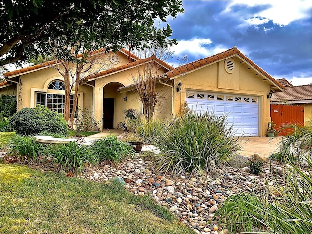 mediterranean / spanish home featuring a garage, a tile roof, and stucco siding