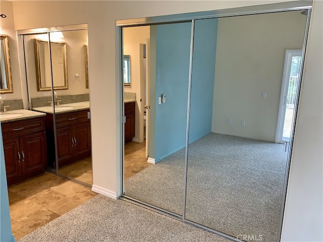 interior space with connected bathroom, a sink, and light colored carpet