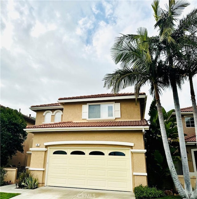 mediterranean / spanish home with driveway, a tile roof, and stucco siding