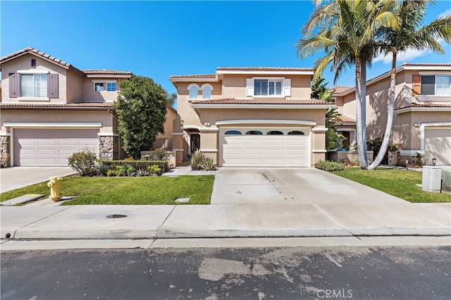 mediterranean / spanish-style home featuring a garage, driveway, a tiled roof, stucco siding, and a front yard