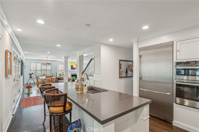 kitchen with dark wood finished floors, dark countertops, stainless steel appliances, a sink, and recessed lighting