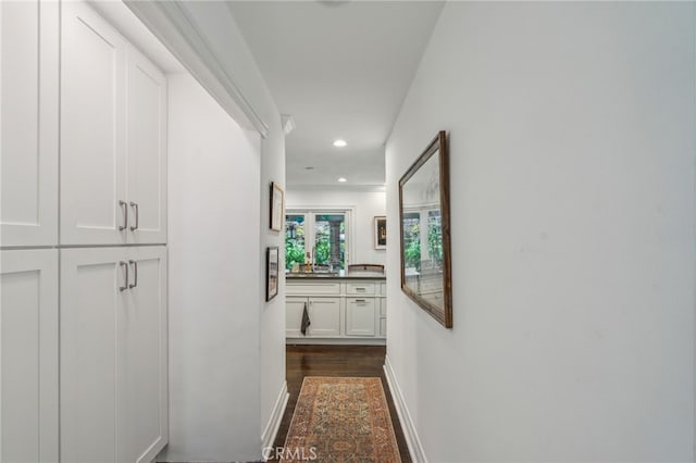 hall featuring baseboards, dark wood-style flooring, and recessed lighting