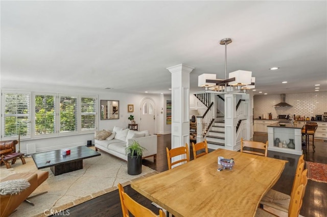 dining space with baseboards, wood finished floors, stairs, ornate columns, and recessed lighting