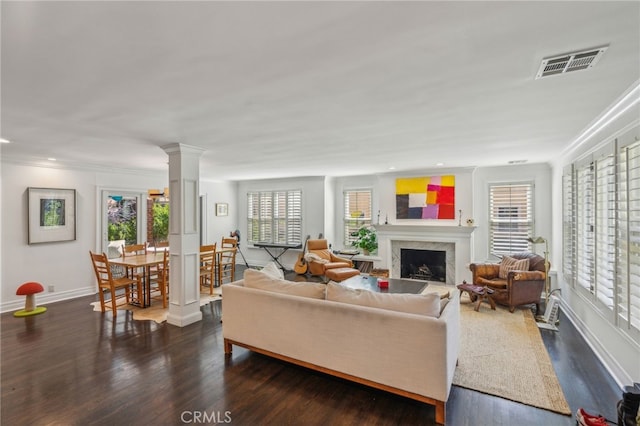 living area with a fireplace, wood finished floors, visible vents, baseboards, and ornate columns