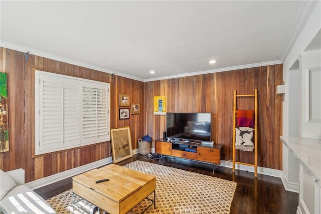 living area featuring crown molding, wooden walls, baseboards, and wood finished floors