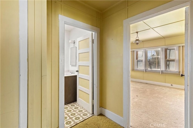 hallway featuring carpet flooring and baseboards