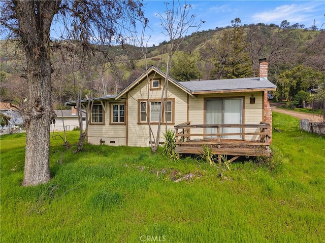 back of property featuring crawl space, a chimney, a lawn, and a wooden deck