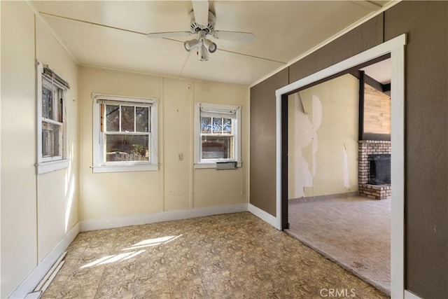 carpeted spare room with ornamental molding, a fireplace, and ceiling fan