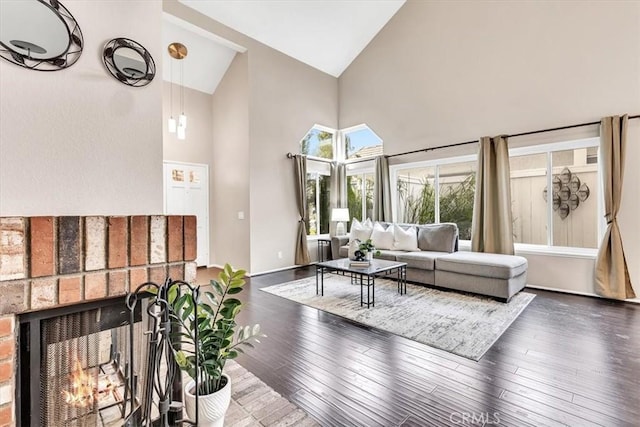 living area with high vaulted ceiling, a fireplace, wood finished floors, and baseboards