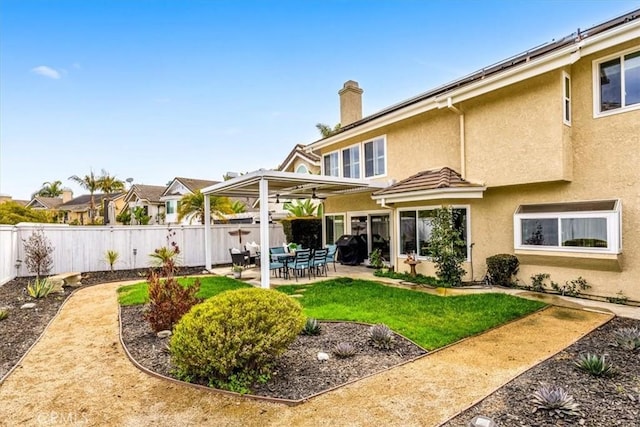 back of property featuring a fenced backyard, a yard, stucco siding, a chimney, and a patio area